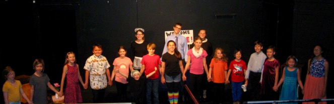Actors onstage wearing costumes, lined up for bows