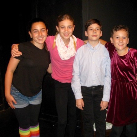 Four actors onstage in costumes, posing for a picture together