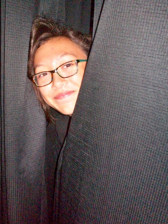 An actor peeking out from behind the curtains