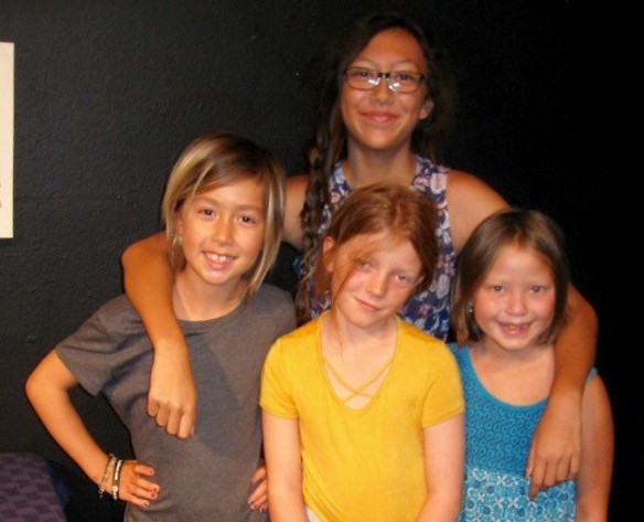 Four smiling actors posing for a picture onstage